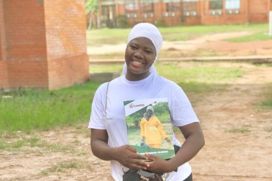 Mabruka, a young Ghanaian woman holds a book and smiles.