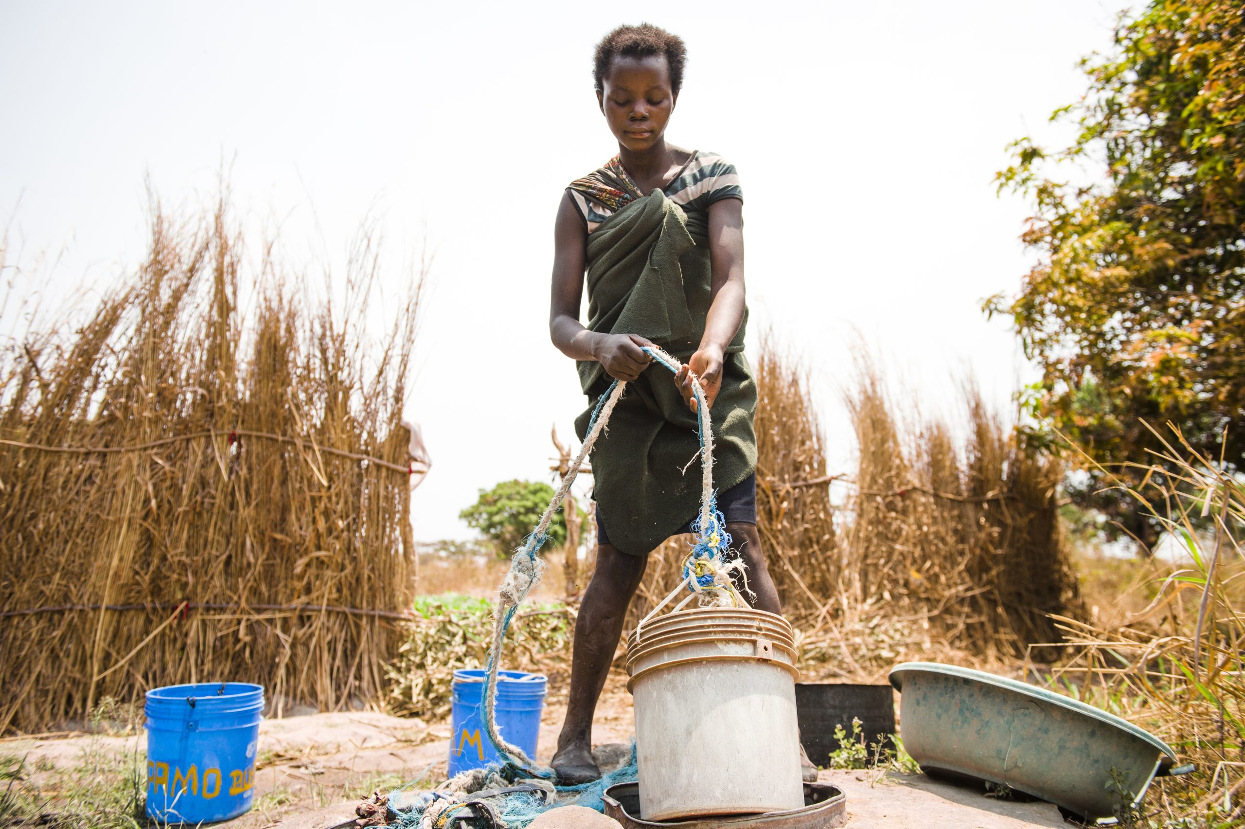 A child bridge collects water from a well, Zambia