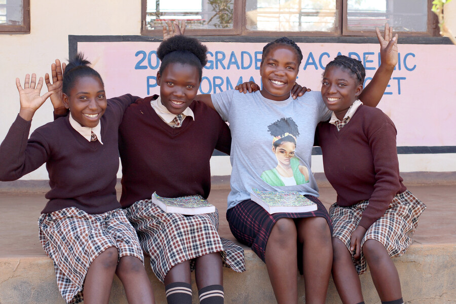 Chise, a Learner Guide in Zambia sits with three students at school.