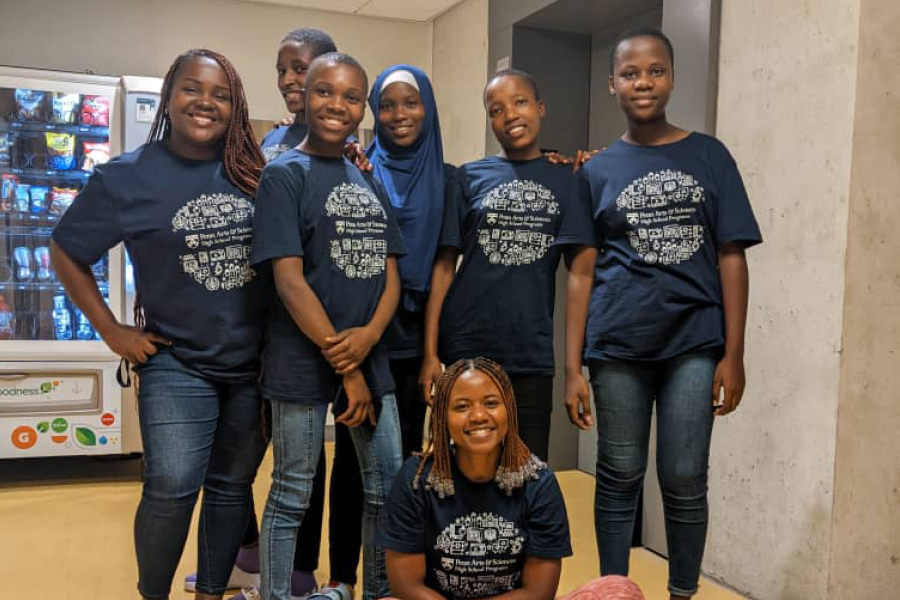 A group of school students and their chaperones smile.