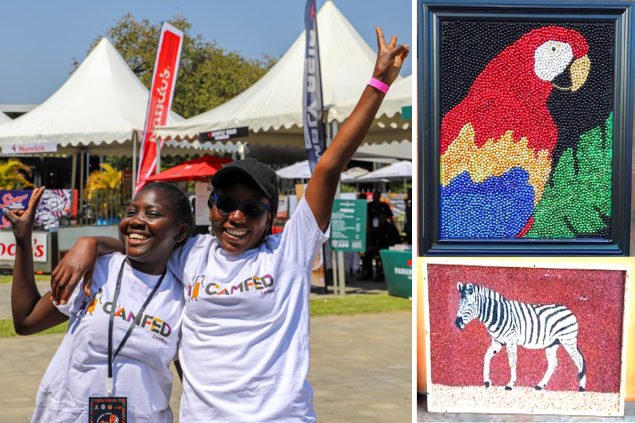 Two Zambian women hug and smile, two colourful mosaics featuring a parrot and giraffe. 